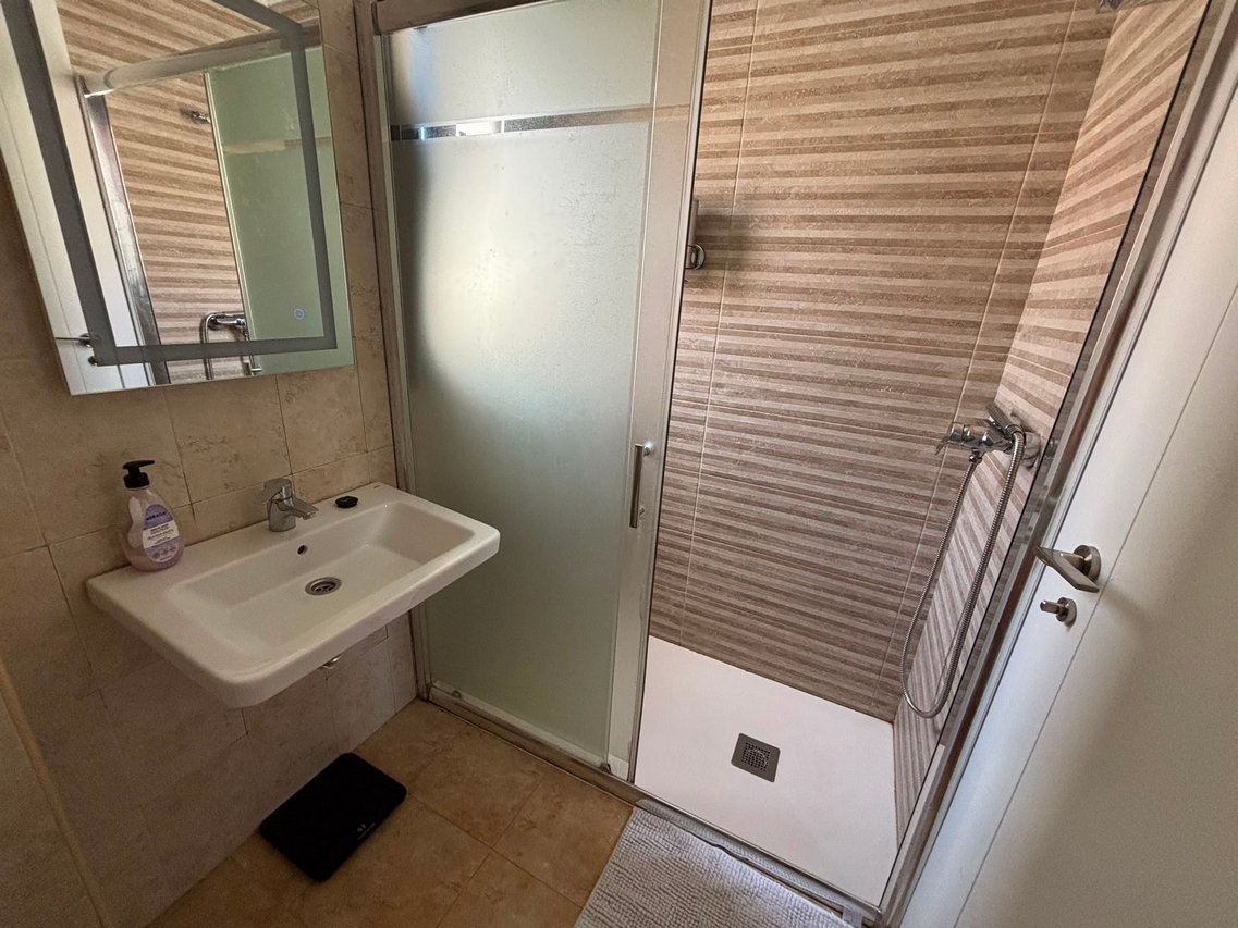 Baño minimalista con lavabo y espejo redondo