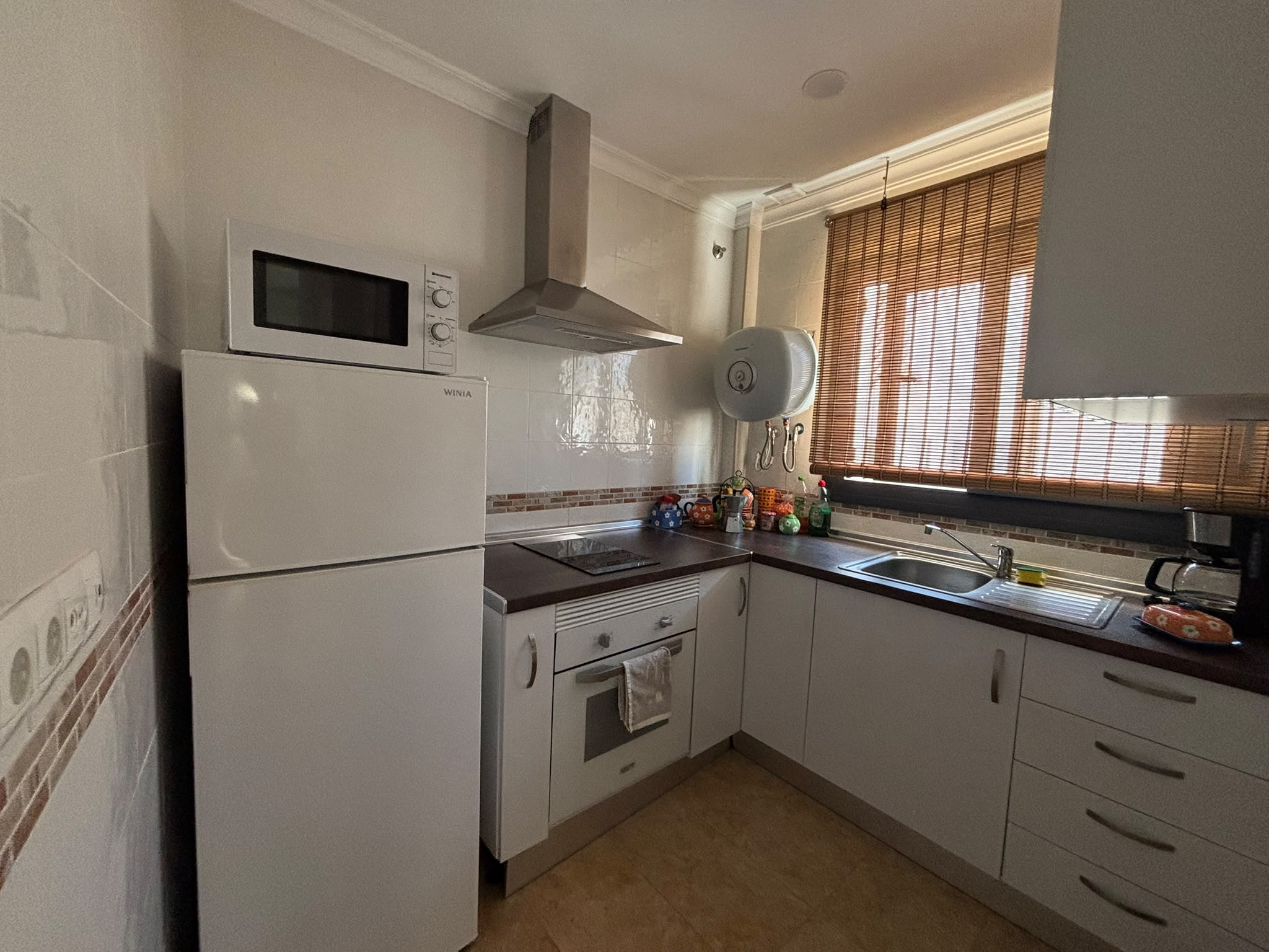 Detalle de la cocina equipada con encimera blanca y utensilios de madera